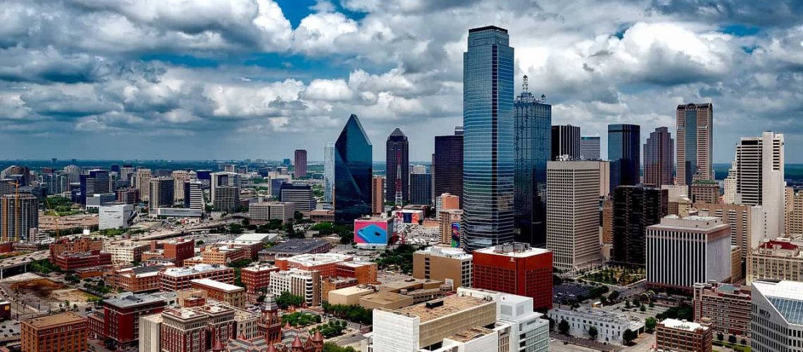 Dallas city skyline with tall buildings and clouds overhead.