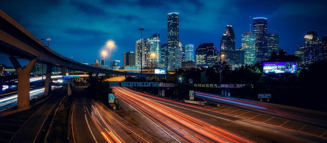 Houston skyline at night with city lights and highway light trails.