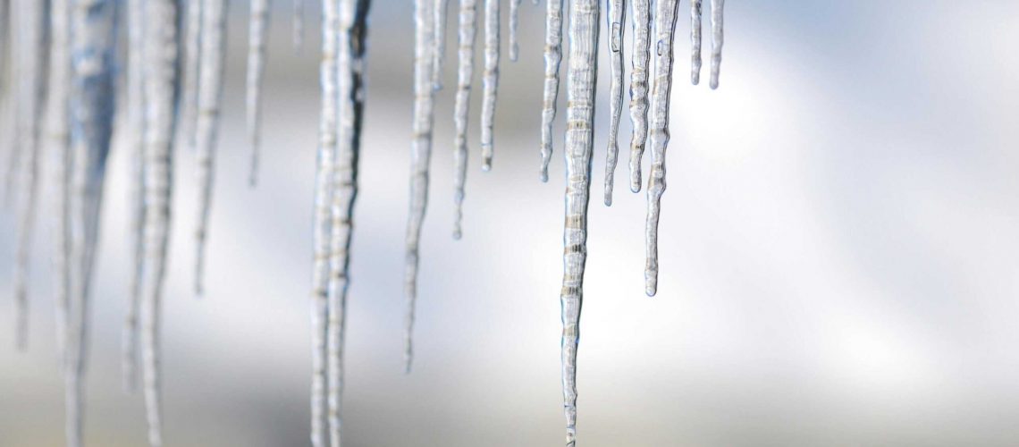 Close-up of icicles hanging from a roof during winter storm.