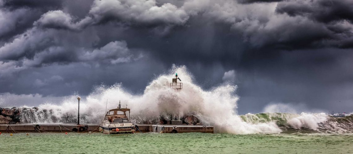 Powerful hurricane storm hitting the coast with large waves and dark storm clouds.