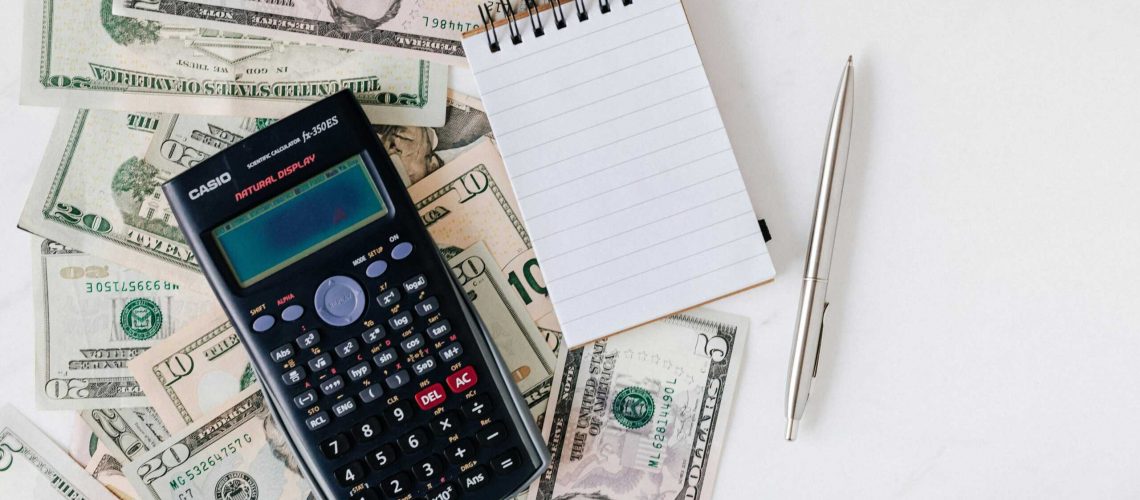 HOA tax filing with calculator, money, notepad, and pen on white background.