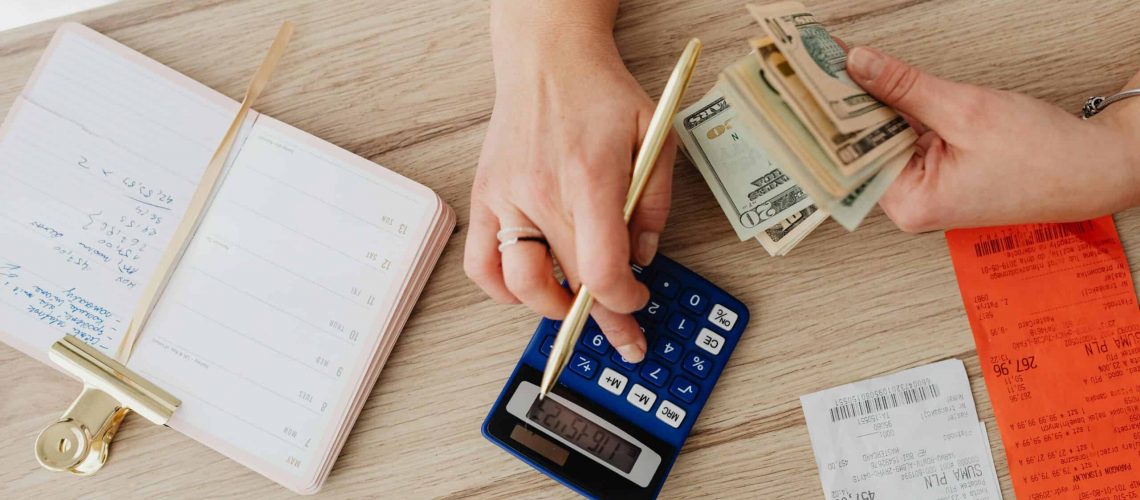 Person using calculator with bills and receipts for HOA financial management.