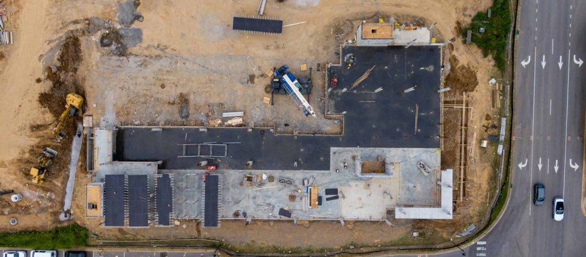 Aerial view of an incomplete residential project with construction equipment and dirt.