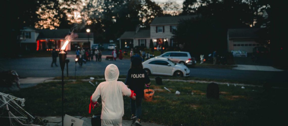 Halloween safety patrol with police presence in neighborhood at dusk.