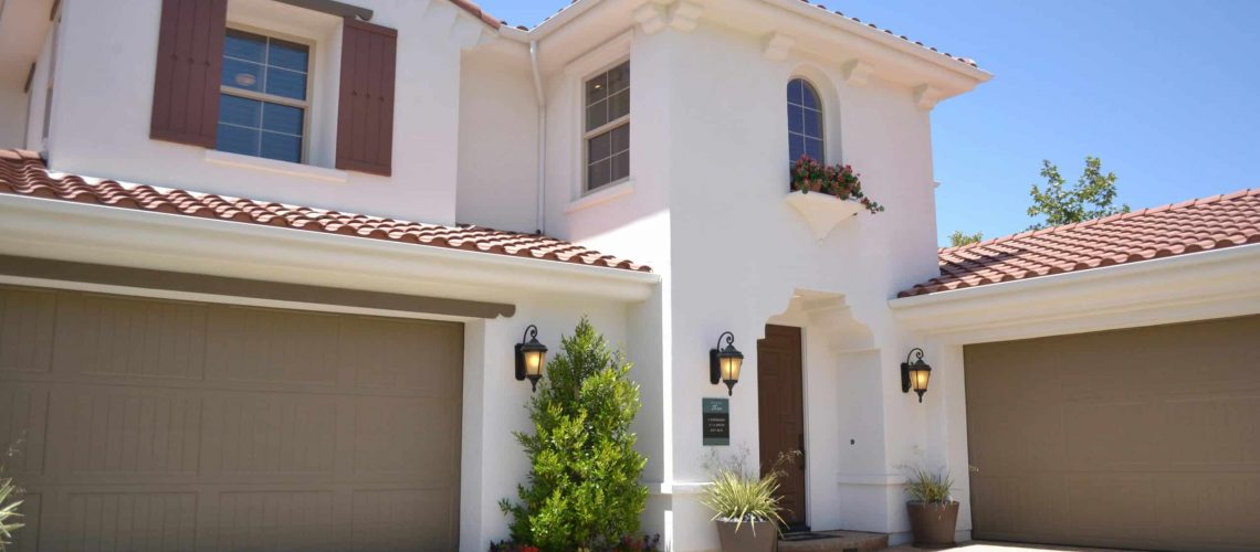 Modern white house with two garage doors and landscaped front yard.