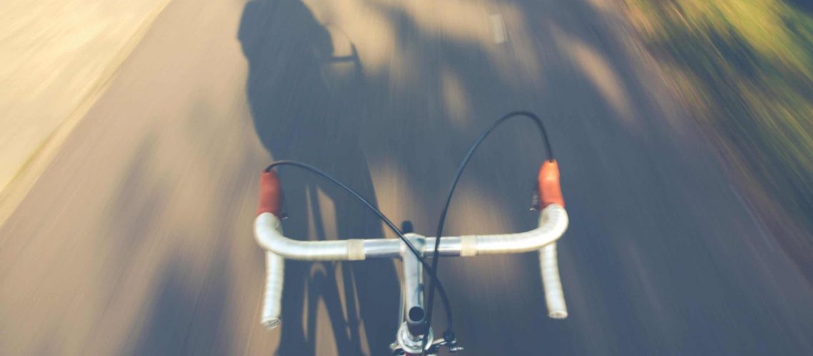 Shadow of cyclist on a blurred road during daytime.