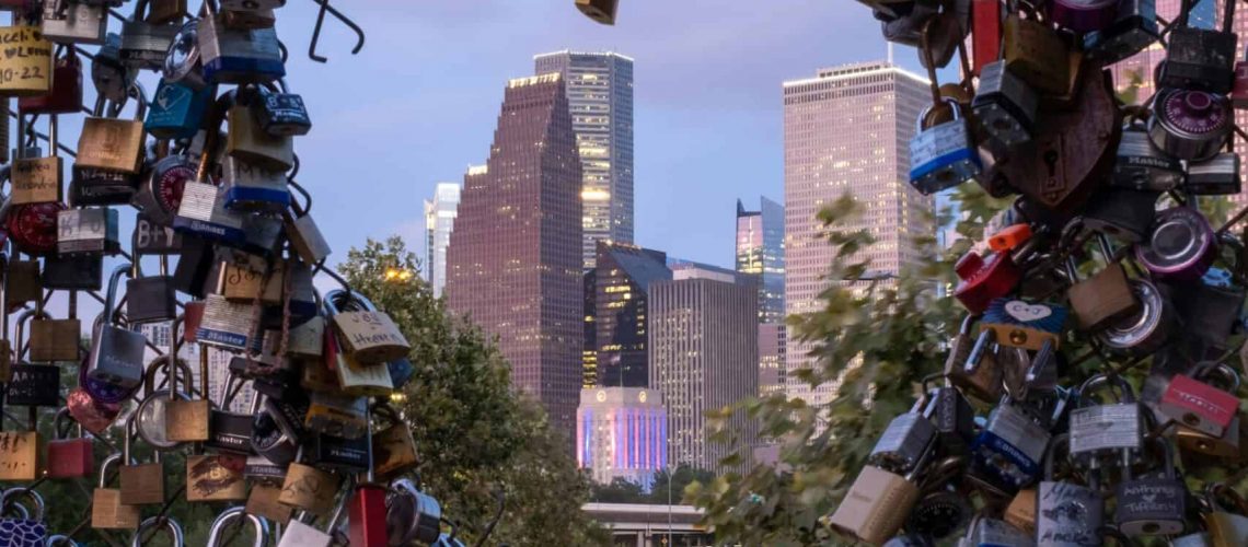Locks on Houston Bridge with city skyline in background.