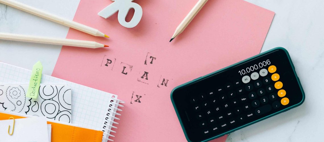 Financial planning with calculator, notes, and pink paper for budget season strategies.