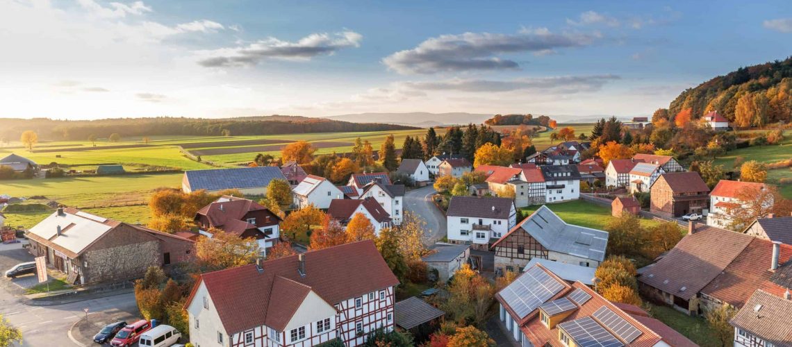 Village community with traditional houses and modern homes in a scenic rural setting.