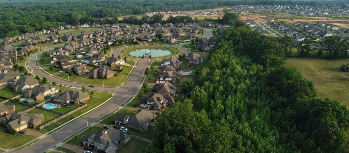 Aerial view of a suburban community showing houses, roads, and surrounding trees.