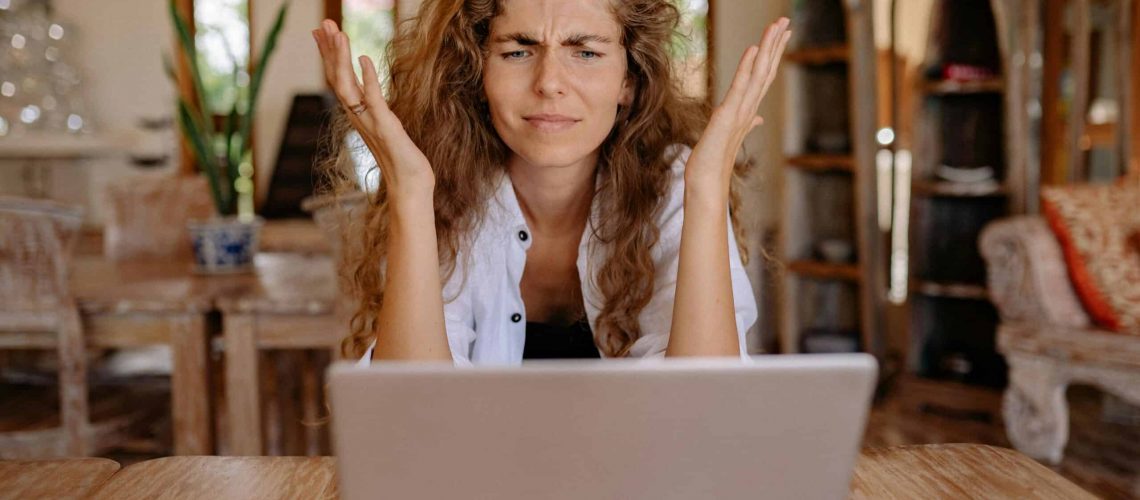 Frustrated woman looking at her laptop, representing HOA community disputes.
