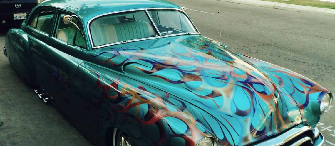 Vintage car with vibrant flame paint design at Houston Art Car Parade 2024.